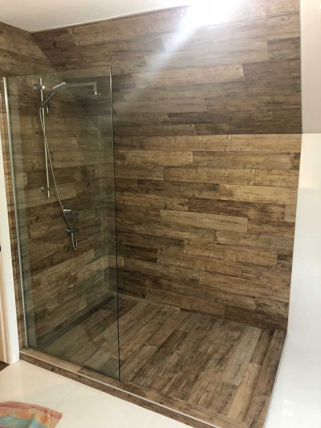 Douche en coin sous plafond mansardé en céramique imitation bois rustique