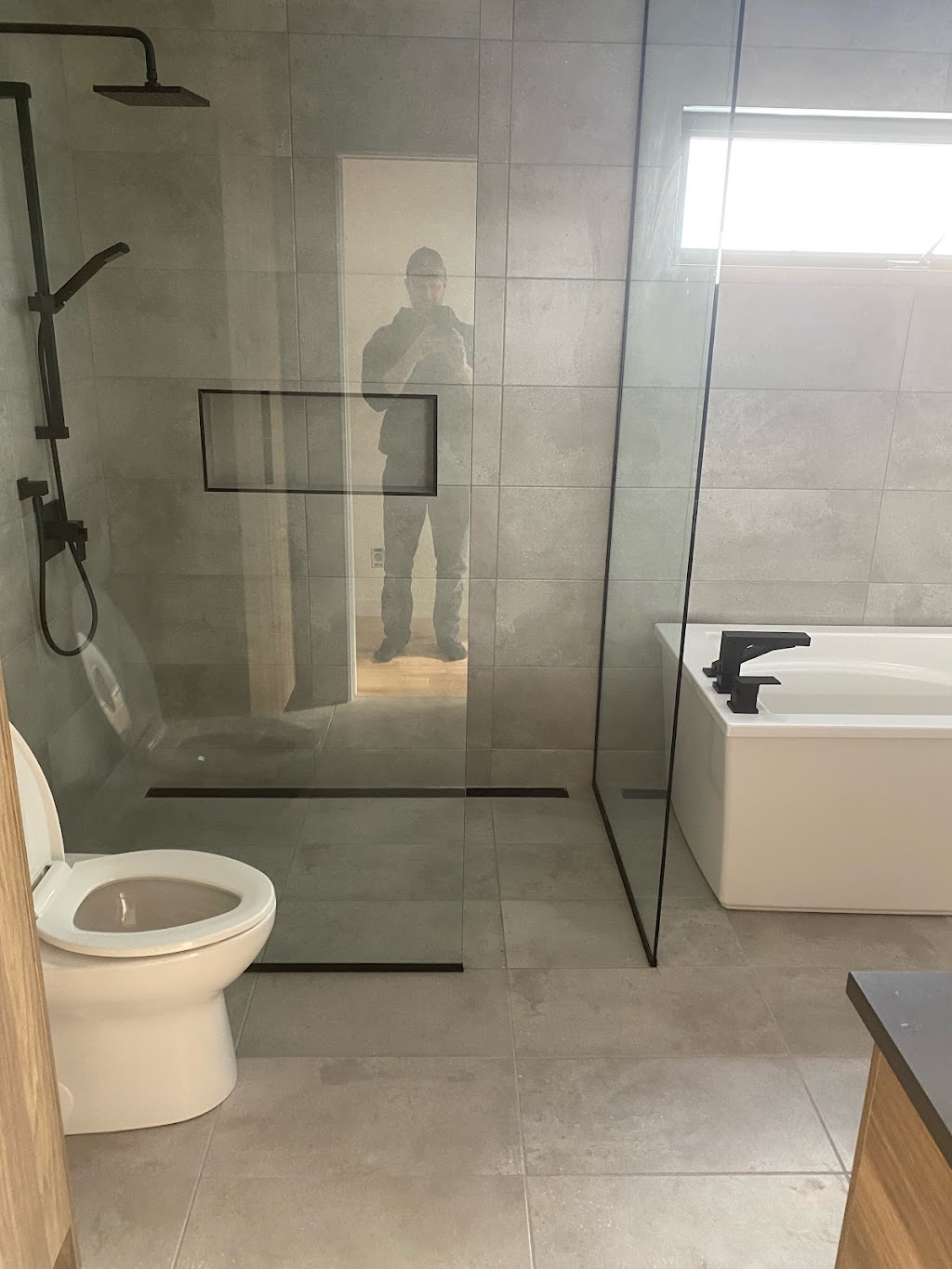 Douche en céramique sur mesure avec drain linéaire et niche encastrée par Céramique Plus
