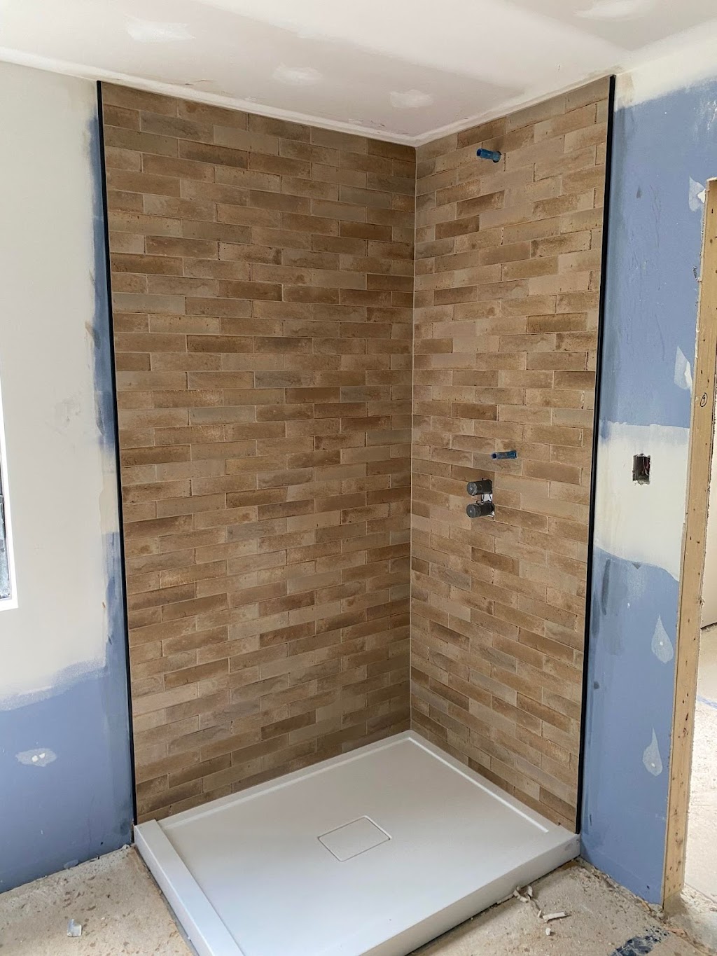 Chantier de pose de céramique de douche avec moulures de finition Schluter noires