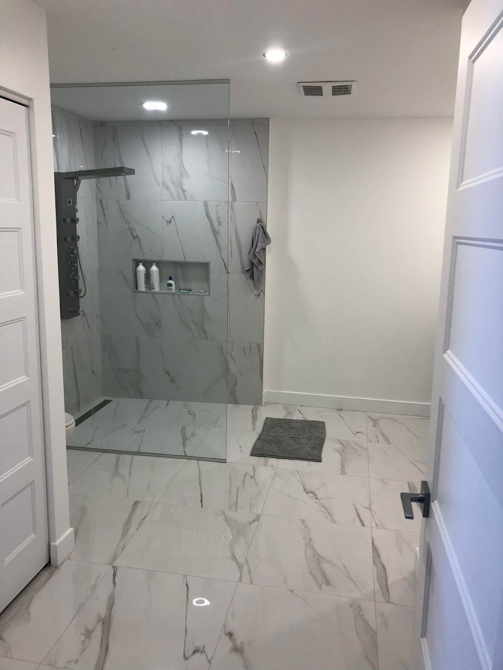 Douche sans seuil curbless en porcelaine effet marbre blanc et drain linéaire
